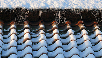 Winter with roof with snow and ice which can damage your roof and require attention from a roofing contractor Sheffield